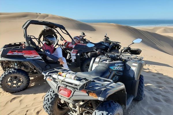 Red buggies and a quad parked on the Tifnit dunes above the Atlantic